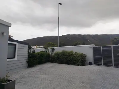 a parking lot in front of a house with mountains at Hermanus C-Escape Apartment in Hermanus