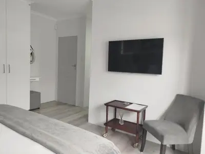 a bedroom with a tv and a chair and a table at Hermanus C-Escape Apartment in Hermanus