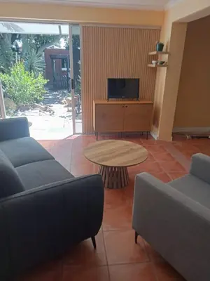 a living room with couches and a table and a tv at Blouberg Holiday Haven in Cape Town