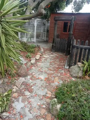 a yard with rocks and a fence and a house at Blouberg Holiday Haven in Cape Town
