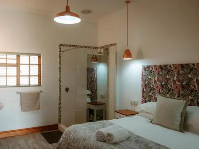 a bedroom with a white bed and a shower at Franschhoek Farm Cottages in Franschhoek