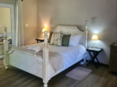 a bedroom with a white bed with two lamps at Franschhoek Farm Cottages in Franschhoek