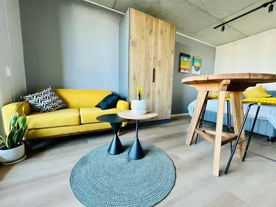 a living room with a yellow couch and a table at Cape Town Studio for business travel in Cape Town