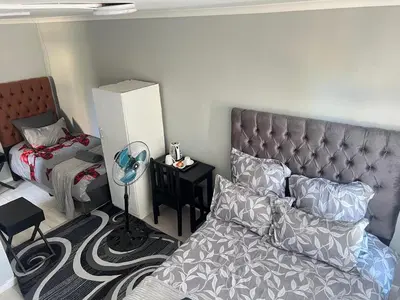 a bedroom with a bed and a table with a fan at HavenTrust Guest house in Goodwood