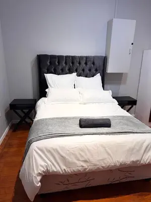 a large bed with a black headboard and white pillows at HavenTrust Guest house in Goodwood