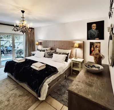 a bedroom with a large bed and a chandelier at Garden Hideaway in Stellenbosch