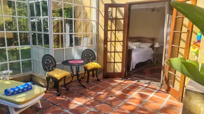 a room with chairs and a table and a bedroom at Sunbird room in Cape Town