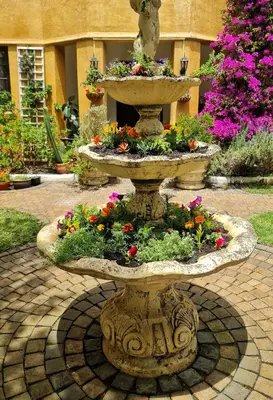 a stone fountain with flowers in a courtyard at Sunbird room in Cape Town