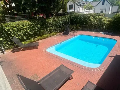 a swimming pool with two chairs on a brick patio at 3 Vilaroux in Stellenbosch
