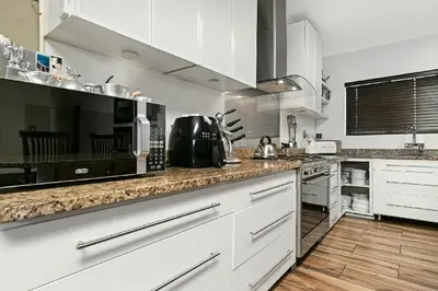 a kitchen with white cabinets and a counter top at Sunset Bliss Villa, Sunset Beach, Cape Town in Cape Town