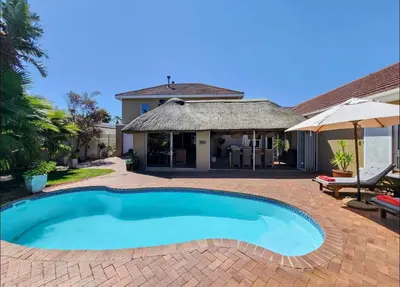 a swimming pool in front of a house at Sunset Bliss Villa, Sunset Beach, Cape Town in Cape Town