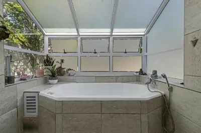 a large bath tub in a room with windows at Sunset Bliss Villa, Sunset Beach, Cape Town in Cape Town