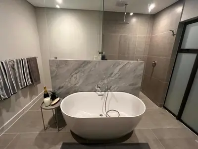a white bath tub in a bathroom with a shower at 18 On Louvre Guesthouse in Paarl