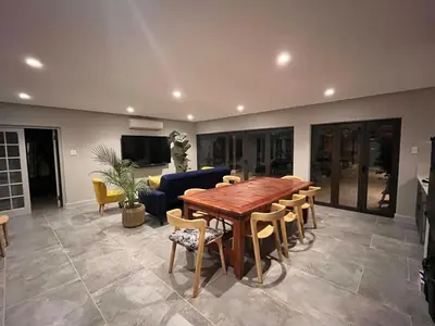a living room with a wooden table and chairs at 18 On Louvre Guesthouse in Paarl