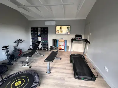 a gym with treadmills and exercise equipment in a room at 18 On Louvre Guesthouse in Paarl