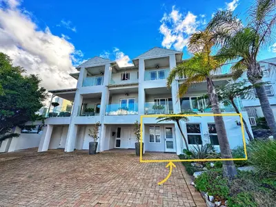 a large white building with a palm tree in front of it at Sea 'n Summit Suite in Hermanus