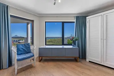 a living room with a desk and a window at ocean12 Guesthouse Sunset Beach in Cape Town