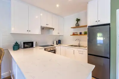 a kitchen with white cabinets and a black refrigerator at Tram Vibes in Franschhoek