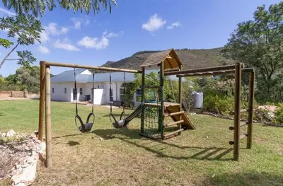 a swing set in a yard with a house at Charming Country Escape with Mountain Views in Hermanus