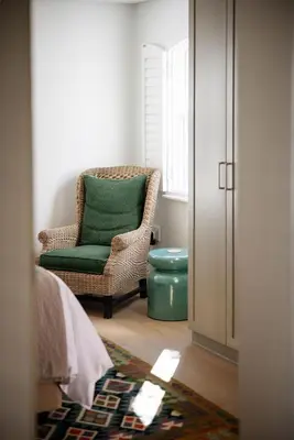 a room with a chair with a green pillow at One on Main in Franschhoek