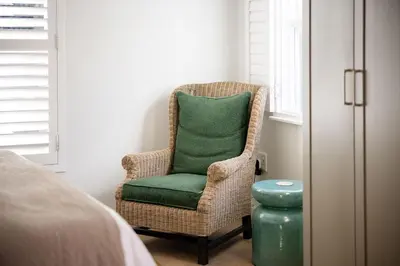 a wicker chair with a green pillow in a bedroom at One on Main in Franschhoek