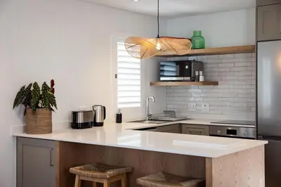 a kitchen with a sink and a counter with stools at One on Main in Franschhoek