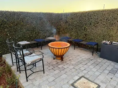 a large fire pit in a patio with chairs and tables at Yellow Wood 1 in Hermanus