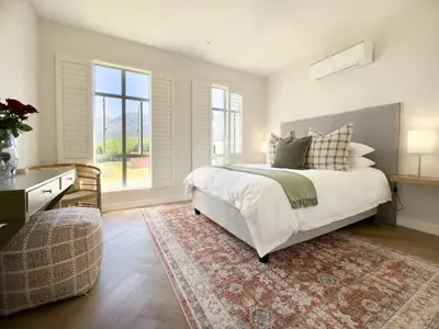 a bedroom with a large bed and a rug at Tre Jolie in Franschhoek
