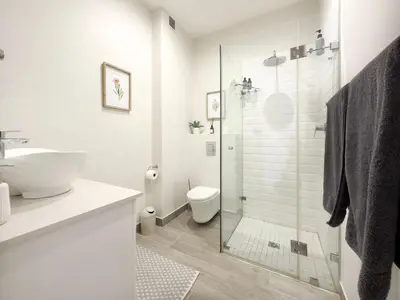 a white bathroom with a shower and a sink at Tre Jolie in Franschhoek