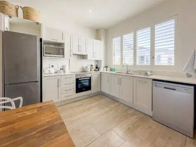 a kitchen with white cabinets and a stainless steel refrigerator at Tre Jolie in Franschhoek