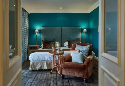 a hotel room with a bed and a chair and a table at The Devon Valley Hotel in Stellenbosch