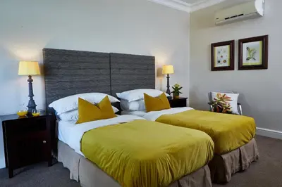 two beds in a hotel room with yellow sheets at The Devon Valley Hotel in Stellenbosch