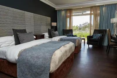 a hotel room with two beds and a chair at The Devon Valley Hotel in Stellenbosch