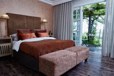 a bedroom with a large bed and a large window at The Devon Valley Hotel in Stellenbosch