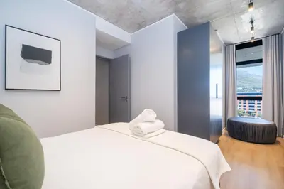 a bedroom with a white bed and a large window at 715 Riverlands - Lux 2 Bedroom Apartment in Cape Town
