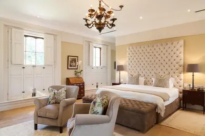 a bedroom with a large bed and two chairs at Lanzerac Hotel & Spa in Stellenbosch