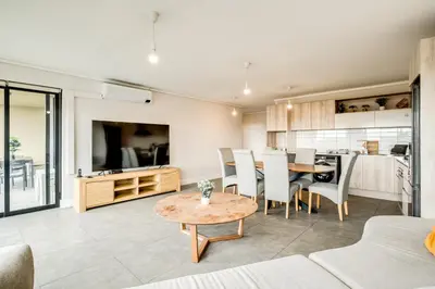 a living room with a table and a kitchen at Belina - Waters Edge Premier in Cape Town