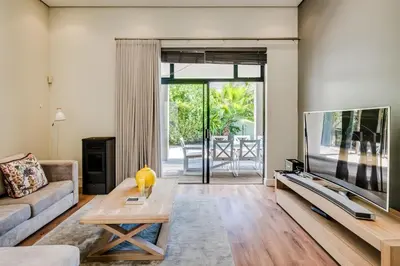 a living room with a large flat screen tv at Belina - Sunset Links Golf Course Villa in Cape Town