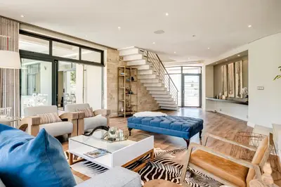 a living room with blue furniture and a staircase at Belina - Sunset Links Golf Course Villa in Cape Town