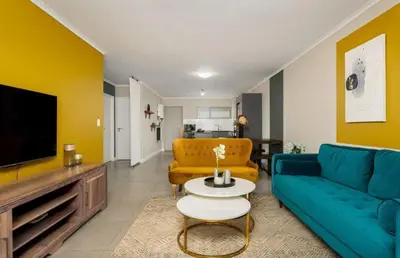 a living room with a blue couch and a tv at Elegant Two Bedroom Apartment in Century City in Cape Town
