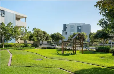 a playground in a park with a building in the background at Elegant Two Bedroom Apartment in Century City in Cape Town