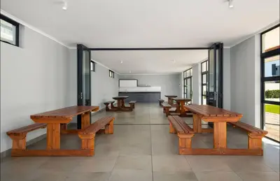 a row of wooden benches in a room with windows at Elegant Two Bedroom Apartment in Century City in Cape Town
