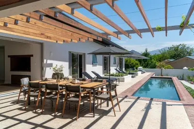 a patio with a wooden table and chairs next to a pool at 6 on Heide in Franschhoek