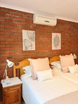 two beds in a bedroom with a brick wall at Nimara de So in Gordonʼs Bay