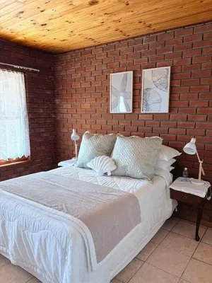 a bedroom with a large bed with a brick wall at Nimara de So in Gordonʼs Bay