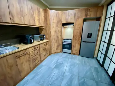 a small kitchen with wooden cabinets and a refrigerator at Modern Van Riebeeck Park Accomodation in Worcester