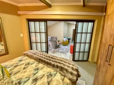 a bedroom with a bed and a living room at Modern Van Riebeeck Park Accomodation in Worcester