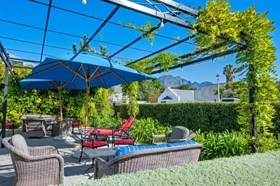 a patio with chairs and an umbrella at La Fontaine Boutique Hotel by The Oyster Collection in Franschhoek