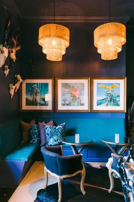 a living room with a blue couch and chandeliers at La Fontaine Boutique Hotel by The Oyster Collection in Franschhoek