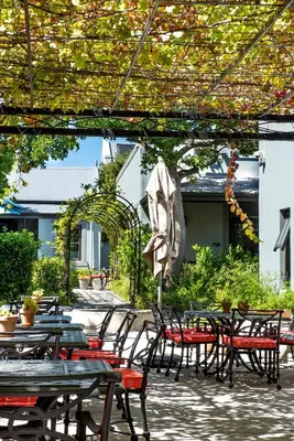 an outdoor patio with tables and chairs and an umbrella at La Fontaine Boutique Hotel by The Oyster Collection in Franschhoek